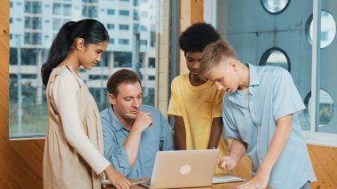 Öğretmen dizüstü bilgisayara bakarken liseli çocuk proje sunuyor. Çeşitli öğrencilerden oluşan bir grup ayakta duruyor ve planı açıklarken akıllı eğitmen de dinliyor ve tavsiye veriyor. Takım çalışması konsepti. Öğretim.
