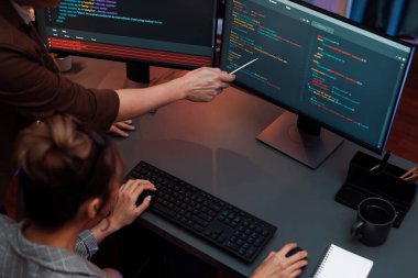 Akıllı web sitesi geliştirme kodlayıcı sistemi ile tartışan IT geliştiricilerinin üst görüşü modern ofisteki neon ışık odasında iki ekran bilgi teknolojisini çevrimiçi çalıştırıyor. İnfobahn.