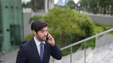 Gülümseyen yakışıklı iş adamı, parkın merdivenlerinde yürürken aynı zamanda işletme müdürünü arıyor. Yatırımcı işe giderken meslektaşıyla konuşuyor. Sevinçli..
