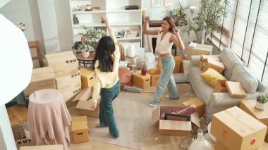 Taşınırken oturma odasında mutlu lezbiyen aşıklar dans ediyor. Birkaç arkadaş müzik eşliğinde salonda karton kutularla dans ederek serbest dans ediyorlar. Yeniden yerleştirme. Myrmidon.