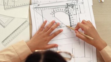 Akıllı mimar ya da akıllı mühendisin ölçüm aracı ve ahşap kalem el kullanarak mimari ofisindeki inşaat isabetinin planının detaylarını yazdığı bir video. Eline odaklan. Tanımlama.