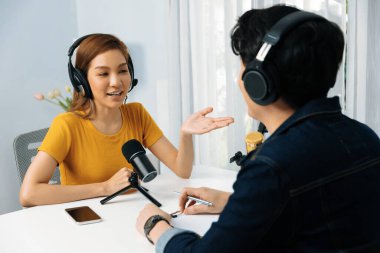 Gülümseyen radyo etkili sunucusu kulaklık takıyor kadın konuşmacı ile röportaj yapıyor sosyal medya internet sitesinden dinleyicilere bilgi paylaşıyor stüdyo kaydında sabah canlı yayın kanalı. İnfobahn.