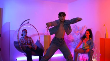 Çok kültürlü bir arkadaş kürsüde otururken Asyalı yetenekli bir dansçı modern müziğe geçiyor. Profesyonel dansçı, hipster takımı tezahürat yaparken ve desteklerken enerjik adımlar atıyor. Mutluluk.