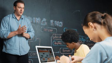 Kafkas öğretmeni alkışlayarak öğrencileri kodlamayı veya programlamayı teşvik etmek için alkışlıyor. Çeşitli öğrenciler STEM sınıfına katılırken başarılı bir projeyi kutlamak için el çırpıyorlar. Öğretim.