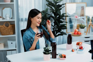 Gülümseyen, güzel Asyalı genç, lezzetli karışık çilek ve kiraz suyu detoksu içeceklerini inceleyen, sosyal medyada özel promosyon satışı için sağlıklı ürünler sergileyen. Taktik.