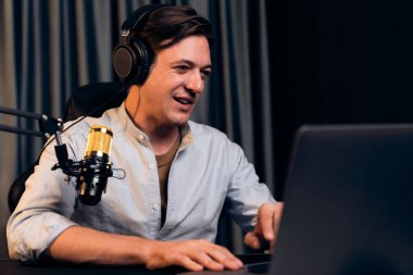 Sunucu kanalı akıllı yayıncı laptopta canlı sosyal medya uygulaması arıyor, kulaklık takıyor ve modern ofis stüdyosundaki mikrofonu kullanıyor. Bireysel.