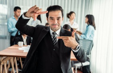 Kameraya bakan mutlu iş adamının portresi, ticari insanların dinamik iş toplantılarındaki hareketlerinin hareket bulanık geçmişine sahip reklam ürünü için el ele hareketler yapıyor. Habiliment