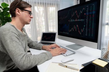 Bilgisayar ve dizüstü bilgisayarı kullanarak, çalışma masasındaki dinamik artırılmış borsa grafiğinin en yüksek kar değerini araştıran bir tüccar, modern ofisteki ekrandaki döviz kuru değerini analiz ediyor. Bireysel.