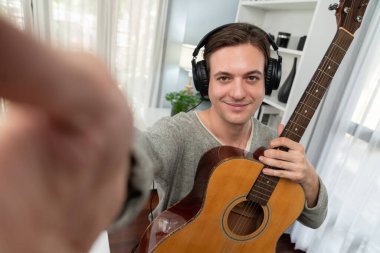 Akıllı şarkıcı görünümlü kamerada sunucu kanalı gitar tutarken, sosyal medya kanalında yayın yaparken, kulaklık takarken modern stüdyo kaydında video kaydedici olarak görülüyor. Bireysel.