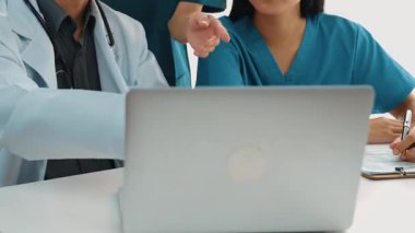 Hastane masasında birlikte çalışan ve tıbbi tedavi planlayan çeşitli profesyonel sağlık görevlileri. Takım çalışması başarılı hastalıklara ve hastalıklara yol açar. Ağır çekim. Katı.