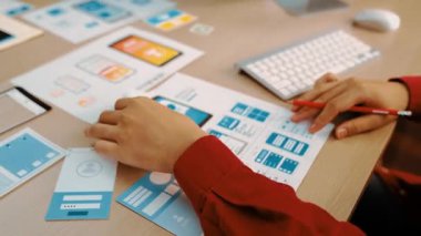 Mobil uygulama için kullanıcı arayüzü prototipini ofis çalışanlarına sunan harika bir şirket çalışanı. UX UI tasarımcısı kağıt üzerinde simge tasarımının işlevini açıklıyor. Sinerjik