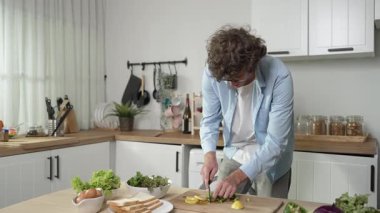 Mutlu baba yemek pişirirken müziğe geçiyor ve modern mutfakta öğle yemeği hazırlıyor. Aktif baba, sebze ve mutfak gereçleri ile çevrili sağlıklı yemek ya da salata yaparken şarkıyla dans ediyor. Pedagoji.