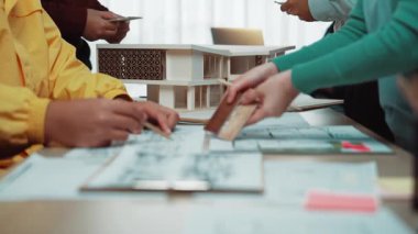 Modern ofisteki dinamik mimari toplantı sahnesi. Profesyoneller, işbirlikçi bir çalışma alanı üzerinde detaylı bir 3D model tasarımı planlayıp tartışıyorlar. SACTR