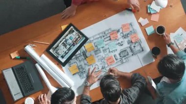 İnşaat mühendisi ekibinin toplantı odasında çalışmaya hazırlanması zaman aşımı. Akıllı mimarın bina inşaatı sırasında masa ve yer proje planında yürüdüğünü en tepeden aşağıya gösteren hava manzarası. Sempozyum.