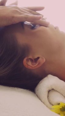 Lüks bir spa merkezinde masaj terapisti tarafından yüz masajı ve spa tedavisi için kaplıcaya uzanmış rahat bir kadın. Sağlık, stres atma ve gençleştirme kavramı.