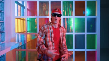 Serbest stil tişört giyerken sokak müziği çalan mutlu hipster. Gece kulübünde neon ışıkla dururken çekici break dansçı dans ve hareketli hareketler yapıyor. Mutluluk.