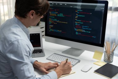 Stresli bilişim geliştiricisi deneme uygulamasında kodlama programı olan bilgisayar ve bilgisayar üzerinde çevrimiçi yazılım geliştirme bilgilerini analiz ediyor. Teknik mühendis önemli not listeleri yazıyor. Bireysel.