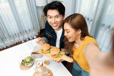 Gülümseyen ev sahibi aşçıların akıllı telefonuyla fotoğraf çekerken üst görüntüsü yemek programında çift hamburger tutarken sosyal medya kanalında ev yapımı salata tabağıyla kolaylıkla görülebiliyor. İnfobahn.