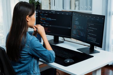Genç Asyalı bilişim geliştiricisi güzel poz için online bilgi topluyor. Kodlama programı verileriyle birlikte kotlu tişört giyiyor. Güvenlik analizi ile çevrili iki ekran. Taktik.