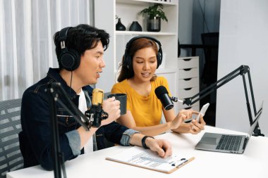 Gülümseyen radyo etkili sunucular, kulaklık takıp sosyal medyayı canlı yayında dinleyicilere telefon ve dizüstü bilgisayarla canlı yayınlıyorlar. İnfobahn.