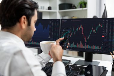 Elinde telefon dinamiğine odaklanan kahve fincanı tutan borsa yatırım ekranı veri analizini karşılaştırarak iç işlerinde yüksek kârlı finans teknolojisi pazarına yatırım yapıyor. Tahmin et..