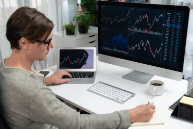 Bilgisayar ve dizüstü bilgisayarı kullanarak, çalışma masasındaki dinamik artırılmış borsa grafiğinin en yüksek kar değerini araştıran bir tüccar, modern ofisteki ekrandaki döviz kuru değerini analiz ediyor. Bireysel.