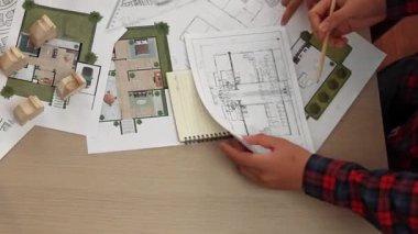 Mimari belge, ölçüm aracı ve ahşap blokların modern ofiste etrafa saçıldığı bir masa üzerinde yapı inşaatı ile ilgili mimar ve güvenlik mühendisi tartışması. Tanımlama.