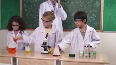 Amerikalı bir kız renkli sıvıyı incelerken erkek beher içine solüsyon döker. Enerjik öğrenci, öğretmenler çocukları keşfederken ve yenilikleri keşfederken arkadaşının deney yapmasına destek oluyor. Pedagoji.