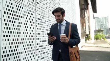 İş adamı telefona cevap verir ve iş yatırımları hakkında konuşur. İş planı, pazarlama stratejisi ya da çalışma hakkında konuşmak için akıllı telefonla konuşurken sokakta yürüyen mutlu bir yönetici. Sevinçli..