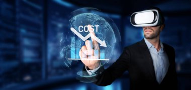 Sanal gerçeklik kulaklığı takan profesyonel bir adam, kurumsal bütçe yönetimi ve finansal stratejileri geliştirmek için maliyet azaltma grafikleri ve eğilimlerini analiz eder. XDMCP