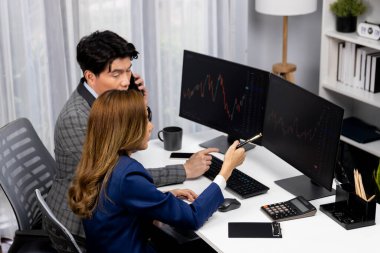 Gülümseyen Asyalı işadamı komisyoncu dinamik borsa veritabanını arıyor. Kadın iş ortağı, iç işyerindeki kar eden uygulama programını karşılaştıran ekranlara işaret ediyor. İnfobahn.