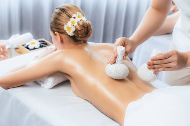 Sıcak bitkisel top spa masaj vücut tedavisi, masör kadın vücuduna nazikçe şifalı bitki torbası bastırıyor. Aromaterapi dinlenme sükuneti ve sükuneti kaplıca salonundaki atmosferi aydınlatıyor. Sessiz.