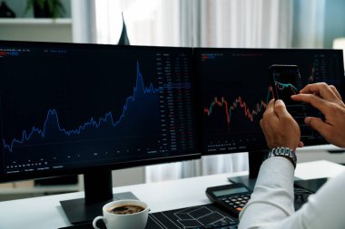 Akıllı telefondan akıllı telefon arayan tüccar işadamı, bilgisayardaki dinamik borsa yatırım ekranını analiz ediyor ve modern merkez ofisteki en kârlı finansal teknoloji pazarına yatırım yapıyor. Tahmin et..