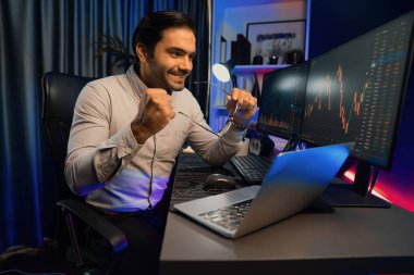 Akıllı tüccar işadamı, karanlık oda gecesinde neon ışıklı ofisteki arama pazarında yüksek kârla ekranda bilgisayar ve bilgisayar üzerinde dinamik borsa yatırımları üzerinde yoğunlaşıyor. Tahmin et..