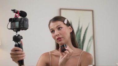 Sosyal medya için güzellik ve kozmetik video içeriği hazırlayan genç bir kadın. Güzellik blogcusu kameraya gülümserken seyircilere ve takipçilere güzellik bakımını gösteriyor. Düzenle