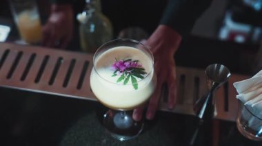 Tutkulu meyveli kokteyl bardağındaki barmen gece hayatı karışımı lüks gece kulübünde özel taze, süslenmiş pembe çiçek pürüzsüz köpük servis ediyor. Vinosity.