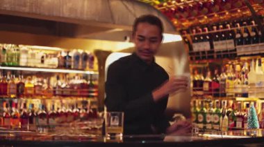 Zeki Asyalı barmen, bardakta karıştırılmış alkol şurubunu buzla karıştırıyor. Lüks gece kulübünde gece hayatı karışımı sergilenen özel bir içecek. Vinosity.