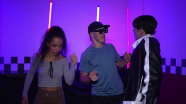 Çok kültürlü break dans takımı mor neon ışıkla stüdyoda müzik yapıyor. Stüdyoda farklı arkadaşlara bakarken serbest dans eden enerjik sokak dansçıları grubu. Çılgınca. Mutluluk.