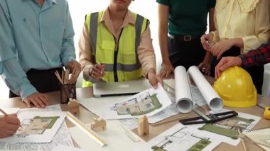 Mimari döküman, ölçüm araçları ve ahşap blokların modern ofiste etrafa saçıldığı masa üzerine planlar yapma konusunda akıllı mimar ve güvenlik mühendisi tartışması. - Yakın çekim. Tanımlama.