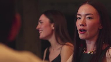 Lüks bir kokteyl barında grup arkadaşıyla gülümseyen güzel bir kadının portresi. Gece kulübünde sosyetik etkileşim için doğal yüz güzelliğini kostüm içinde yakalamak. Vinosity.