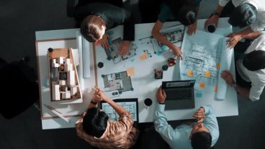 Üst düzey hava görüşlü iş adamları ev modeli ve dizüstü bilgisayarla iç mekan inşaatı hakkında beyin fırtınası yaparken mimar mühendisi de tasarım ve yazım işlerini planladı. Hizalama.