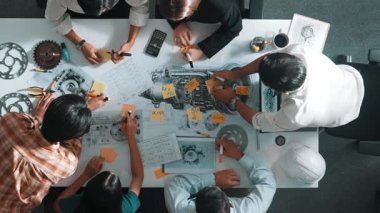 Üstten görünüşlü akıllı mühendis ekibi metal teçhizatlı, hesap makineli, yapışkan notlu türbin motor yapısı hakkında konuşuyor. Bir grup teknisyen toplantıda not alıyor. Hizalama.