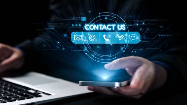 Bir iş adamı iletişim bilgilerine erişirken akıllı telefonla iletişim kurar. Dijital simgeler cihazın etrafını sarar, profesyonel ortamdaki modern iletişim yöntemlerini sembolize ederler. Dörtgen