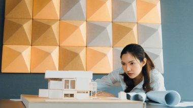 Ofisteki ev modelini kontrol ederken Asyalı profesyonel mimar kadın mühendisin portresi. Emlak evini kontrol ediyorum. İş tasarımı ve inşaat konsepti. Yönlendirici.