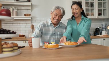 Büyükannem kahvaltısını sunarken, gülümseyen büyükbaba masada oturuyor. Yaşlı çift konuşuyor ve birlikte vakit geçiriyorlar ya da birlikte destek oluyorlar. Sağlıklı ilişki kavramı. Myrmidon.