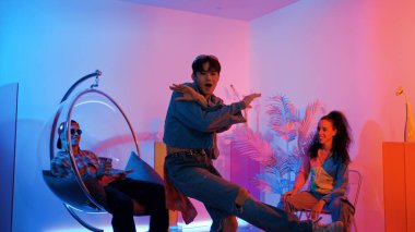 Çok kültürlü bir arkadaş kürsüde otururken Asyalı yetenekli bir dansçı modern müziğe geçiyor. Profesyonel dansçı, hipster takımı tezahürat yaparken ve desteklerken enerjik adımlar atıyor. Mutluluk.