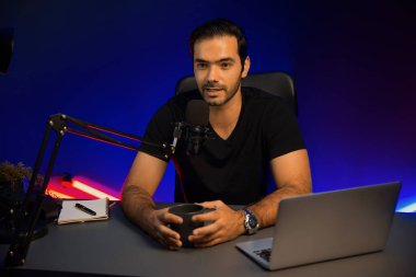 Yayıncı, fanclub dinleyicisiyle mikrofon kullanarak konuşuyor. Mor neon ışıklı modern stüdyoda yaratıcı olumlu düşünce konseptiyle canlı yayında finansal sorunları tartışıyor. Tahmin et..