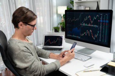 Akıllı borsa yatırımcıları ekranda akıllı telefon ile piyasa borsasını işaret ederek dizüstü bilgisayarın yanı sıra en yüksek dinamik yatırım oranını göstererek, modern işyerindeki veri planlamasına odaklanıyorlar. Bireysel.