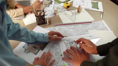 Mimari döküman, ölçüm araçları ve ahşap blokların modern ofiste etrafa saçıldığı masa üzerine planlar yapma konusunda akıllı mimar ve güvenlik mühendisi tartışması. - Yakın çekim. Tanımlama.