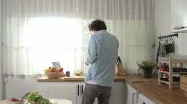 Mutlu baba yemek pişirirken müziğe geçiyor ve modern mutfakta öğle yemeği hazırlıyor. Aktif baba, sebze ve mutfak gereçleri ile çevrili sağlıklı yemek ya da salata yaparken şarkıyla dans ediyor. Pedagoji.